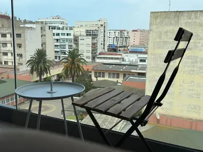 a table and chair on a balcony with a view of a city at Modern City Centre Apartment in Casablanca