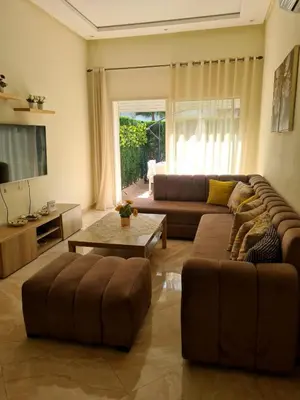 a living room with a couch and a table at Appartement résidence kettani jardin privatif accès direct piscine et aire de jeu in Bouznika