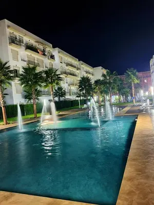 a swimming pool with fountains in front of a building at Appartement résidence kettani jardin privatif accès direct piscine et aire de jeu in Bouznika