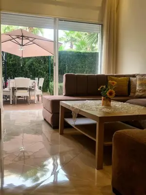 a living room with a couch and a table at Appartement résidence kettani jardin privatif accès direct piscine et aire de jeu in Bouznika