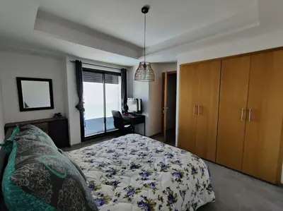 a bedroom with a bed and a desk and a window at Blue Themed Vacation Condo in Temara