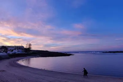 a person walking on the beach at sunset at Blue Themed Vacation Condo in Temara