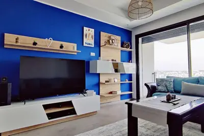 a living room with a blue wall with a flat screen tv at Blue Themed Vacation Condo in Temara