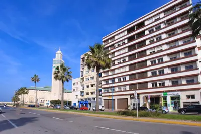 a large white building with a clock tower and palm trees at At Casablanca 's Home in Casablanca