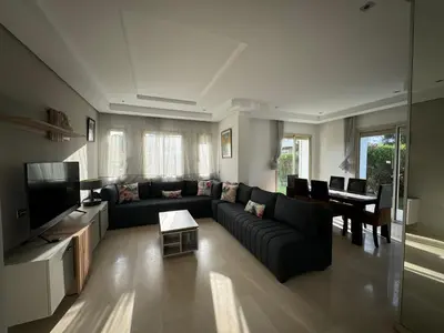 a living room with a black couch and a television at Golf City Prestigia Bouskoura in Bouskoura