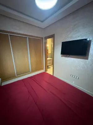 a room with a red bed and a flat screen tv at Douce escale vue sur piscine - Costa Beach bouznika in Bouznika