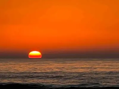 a sunset over the ocean with the sun setting at Villa Taroub avec piscine et vue sur mer in Temara