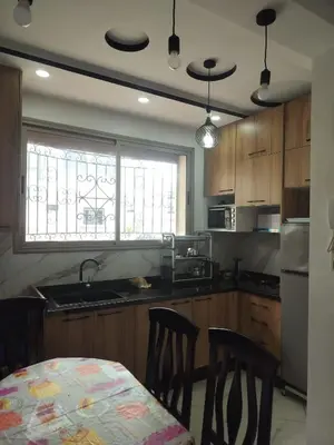 a kitchen with wooden cabinets and a table with chairs at Dahomey city in Bouznika