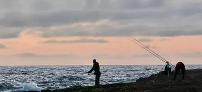 two people fishing on the shore of the ocean at Appartement balnéaire magnifique à Mohammedia Mansouria in Mansouria