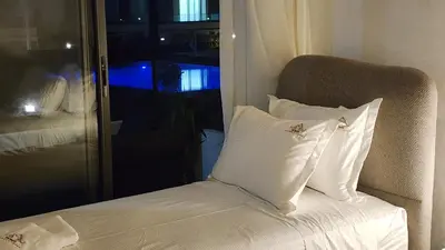 a bed with white pillows and a chair with a window at Appartement balnéaire magnifique à Mohammedia Mansouria in Mansouria