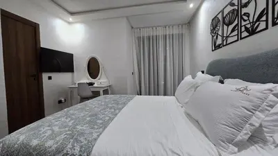 a bedroom with a white bed and a desk at Appartement balnéaire magnifique à Mohammedia Mansouria in Mansouria