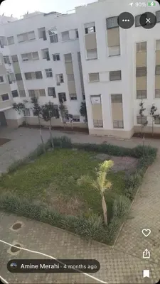 a large white building with a palm tree in front of it at Zen and cosy Appart Rose Marie Kasbah in Skhirat