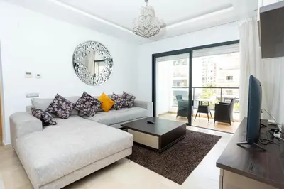 a living room with a couch and a television at Appartement avec piscine in Rabat