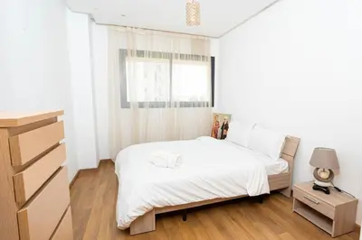 a white bedroom with a bed and a window at Appartement avec piscine in Rabat