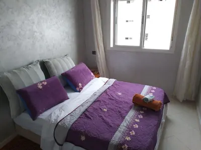 a bedroom with a bed with purple sheets and a window at Omarex in Casablanca