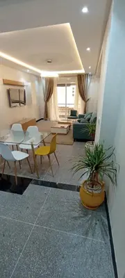 a living room with a table and chairs and a couch at Appart RABAT AGDAL in Rabat