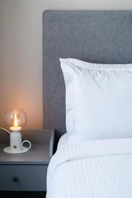 a bed with a white pillow and a lamp on a night stand at Atlantic View Appart'Hotel in Casablanca