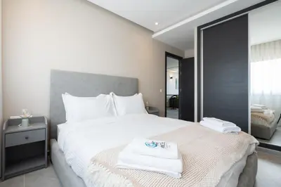 a bedroom with a large white bed with a mirror at Atlantic View Appart'Hotel in Casablanca