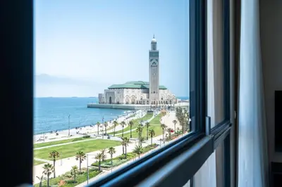 a window with a view of a clock tower and the ocean at Atlantic View Appart'Hotel in Casablanca