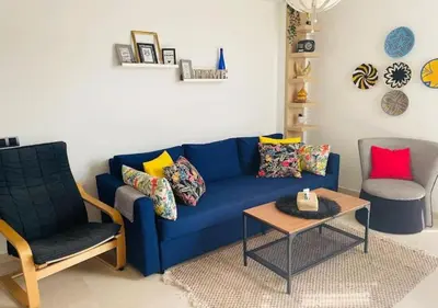 a living room with a blue couch and two chairs at Bel Appartement Cosy dans le centre de Casablanca in Casablanca