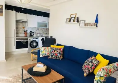 a living room with a blue couch and a kitchen at Bel Appartement Cosy dans le centre de Casablanca in Casablanca