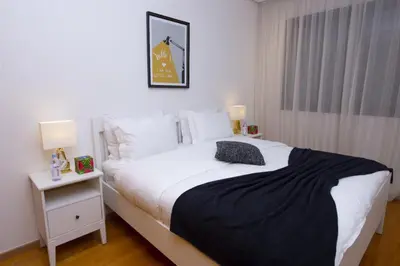 a bedroom with a white bed with a black blanket at Appartement raffiné dans un quartier de luxe in Rabat
