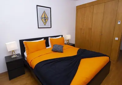 a bedroom with a large bed with orange pillows at Appartement raffiné dans un quartier de luxe in Rabat