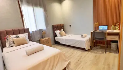 a room with two beds and a desk with a computer at Classic & Comfy Apartment, Steps to Sea & Tarmway in Rabat