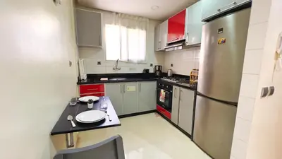 a kitchen with a stainless steel refrigerator and red cabinets at Classic & Comfy Apartment, Steps to Sea & Tarmway in Rabat