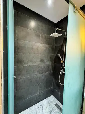 a bathroom with a shower with a black wall at Classic & Comfy Apartment, Steps to Sea & Tarmway in Rabat
