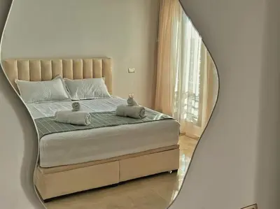 a mirror reflecting a bed with two towels on it at Séjour Chic - Appartement Moderne avec Piscine in Bouznika