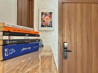 a stack of books sitting on a table next to a door at Séjour Chic - Appartement Moderne avec Piscine in Bouznika