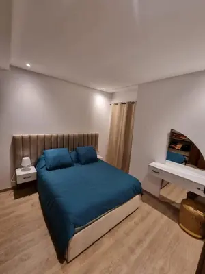 a bedroom with a large bed with blue pillows at Appartement - Dar Bouazza in Dar Bouazza