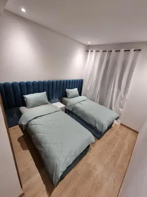 a bedroom with two beds and a blue couch at Appartement - Dar Bouazza in Dar Bouazza