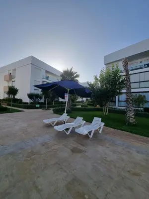 two chairs and an umbrella in front of a building at Appartement - Dar Bouazza in Dar Bouazza