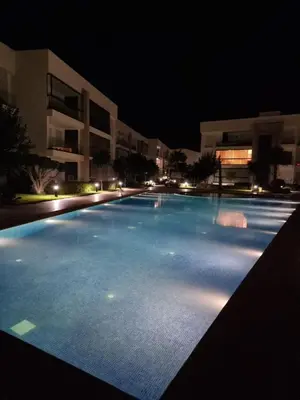 an empty swimming pool at night with buildings at Appartement - Dar Bouazza in Dar Bouazza