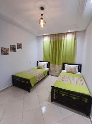 two beds in a room with green curtains at Appartement Sidi Rahal à Garden beach2 in Sidi Rahal