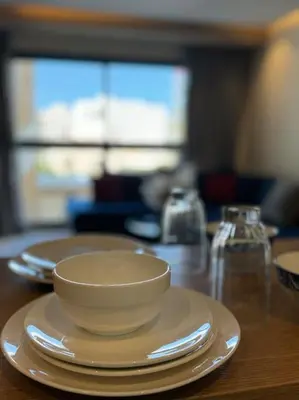 a white bowl and plates on a wooden table at Classy presidential apartment in Casablanca
