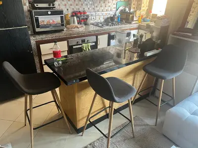 a kitchen with a counter with three chairs at it at Confort repos et belle vue mer in Bouznika