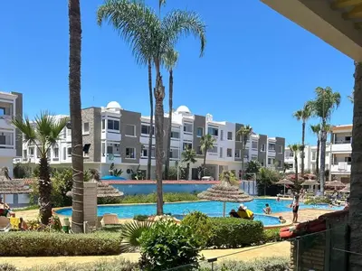 a view of a resort swimming pool with palm trees at Appartement haut standing près de la Plage in Skhirat