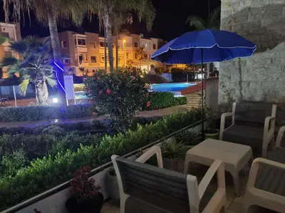 a patio with a table and a blue umbrella at Appartement haut standing près de la Plage in Skhirat
