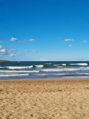 a sandy beach with waves in the ocean at Appartement haut standing près de la Plage in Skhirat