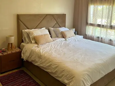 a bedroom with a large bed with white sheets and pillows at Appartement haut standing près de la Plage in Skhirat