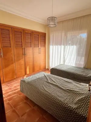 a bedroom with two beds and wooden cabinets at Appartement de H standing in Bouznika