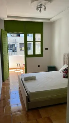 a bedroom with a bed with green doors and a table at Grenn appt in Rabat