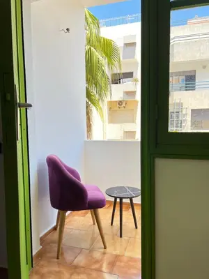 a purple chair and a table in a room at Grenn appt in Rabat