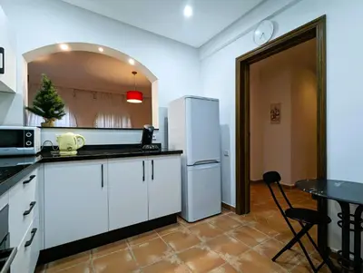a kitchen with white cabinets and a white refrigerator at Appartement de plain-pied, piscine et mer in Bouznika