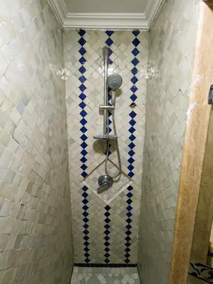 a bathroom with a shower with blue and white tiles at Appartement de plain-pied, piscine et mer in Bouznika