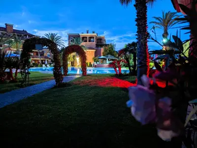 a resort with a pool and palm trees at night at Appartement de plain-pied, piscine et mer in Bouznika