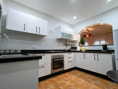 a large kitchen with white cabinets and appliances at Appartement de plain-pied, piscine et mer in Bouznika
